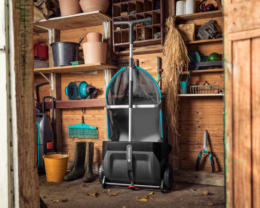 Gardena Lawn and Leaf Collector folded up and stored in a wooden shed with various gardening equipment.