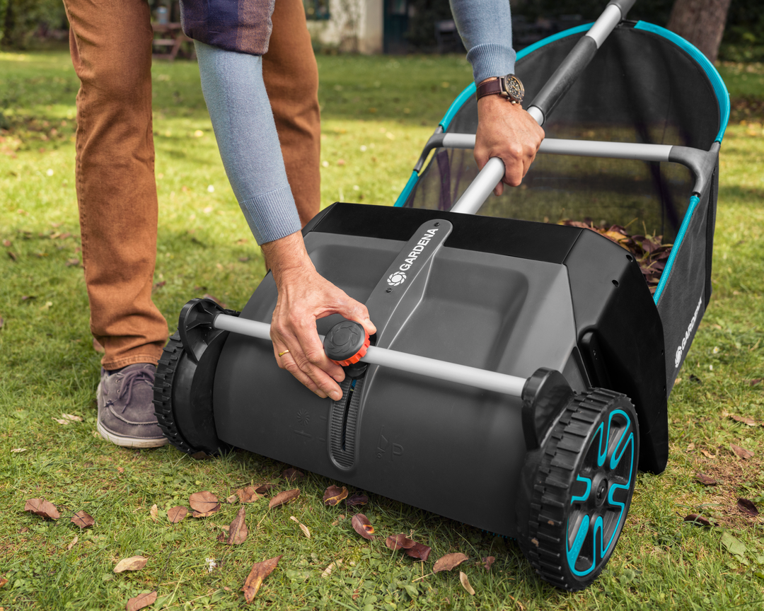 Person using a Gardena Leaf and Lawn Collector to collect leaves on a grassy area