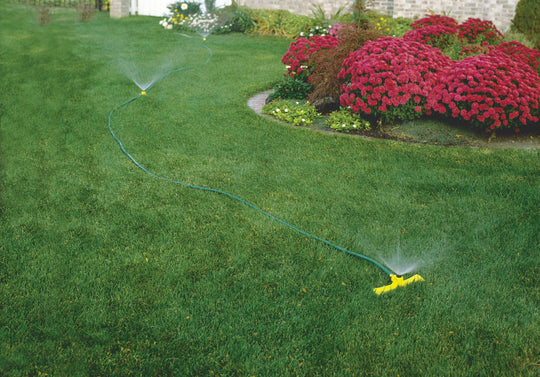 Port-a-rain watering sprinkler system set up in a yard spraying water.