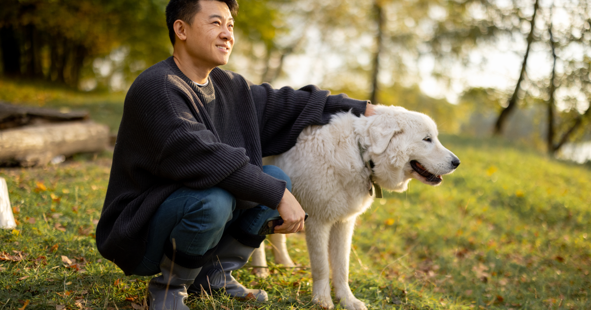 Man with dog sitting on grass. 