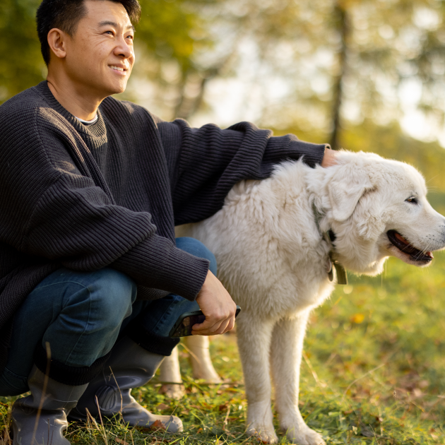 Man with dog sitting on grass. 