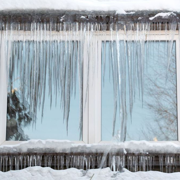Ice dam and icicles draping down window on home. 