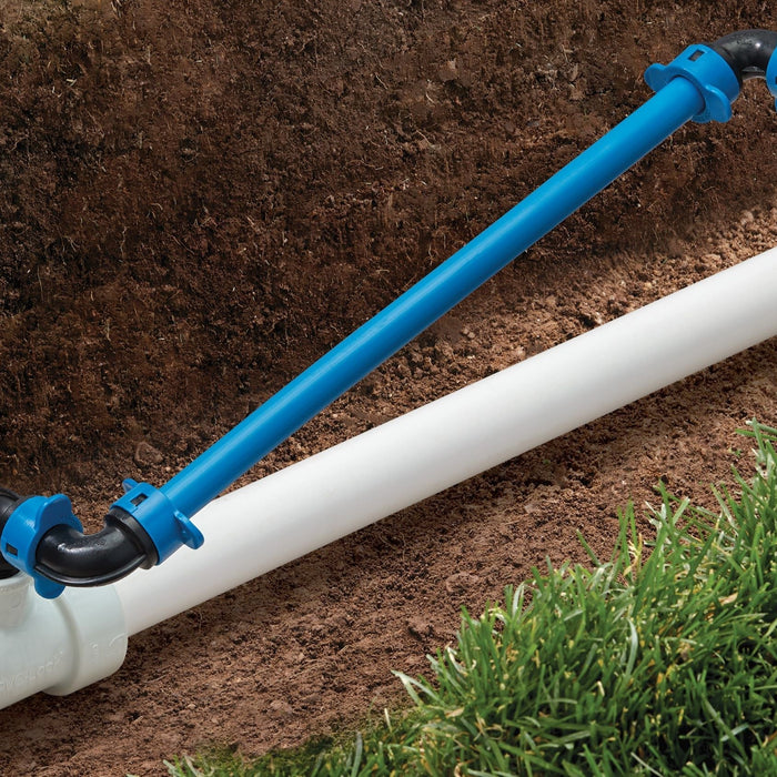 White PVC pipe with PVC-Lock and Blu-Lock irrigation fittings lying in dirt trench next to grass