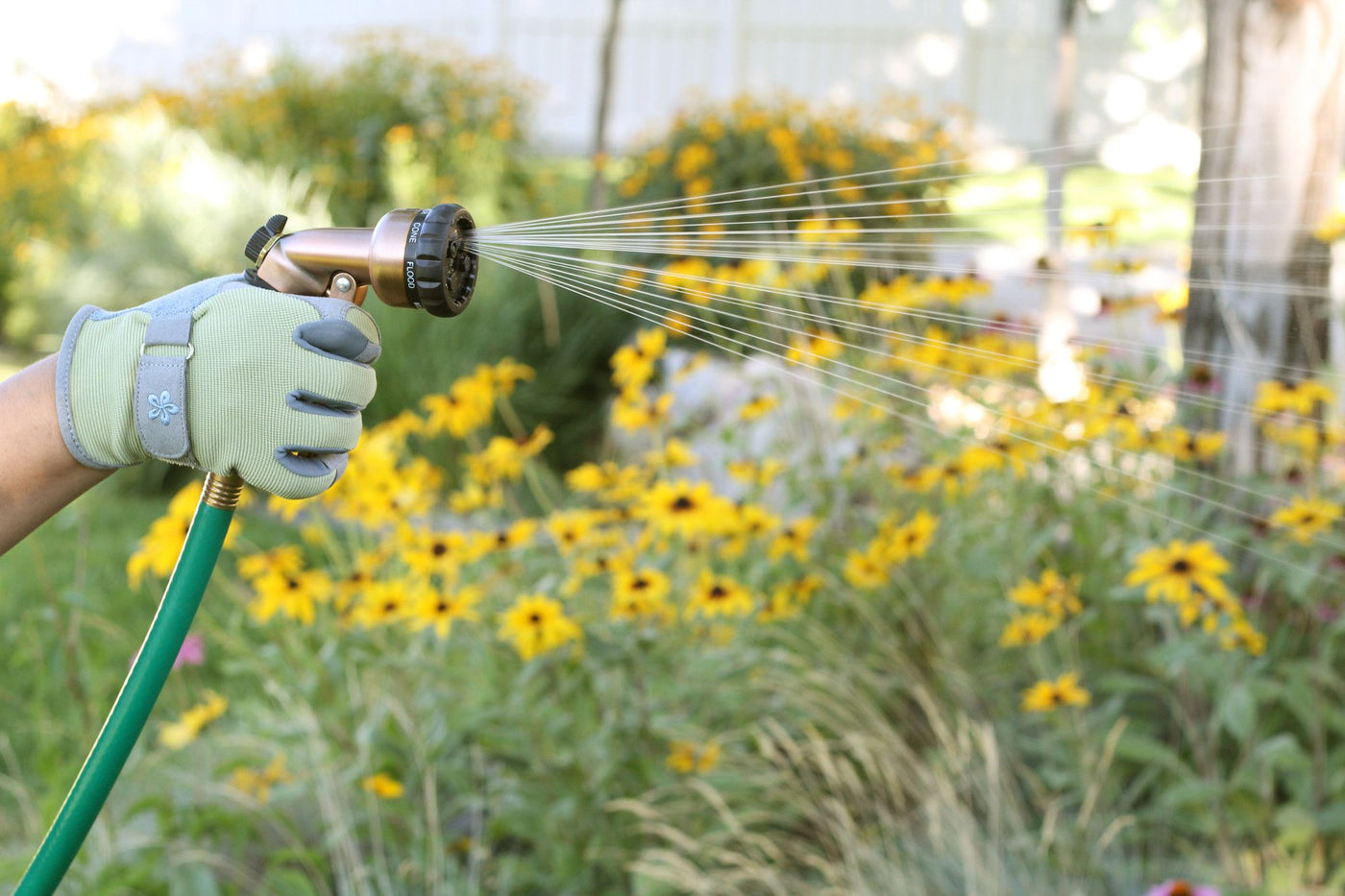 Copper colored seven pattern zinc front trigger nozzle emitting a fan spray pattern of water.