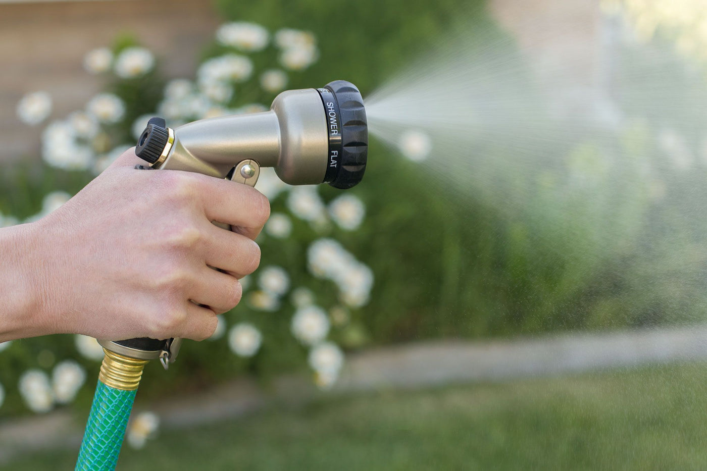 Titanium colored seven pattern zinc front trigger nozzle, emitting a mist of water. 