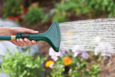 Green plastic fan spray shower nozzle with shut-off lever and spike, emitting a rain-like spray of water. 