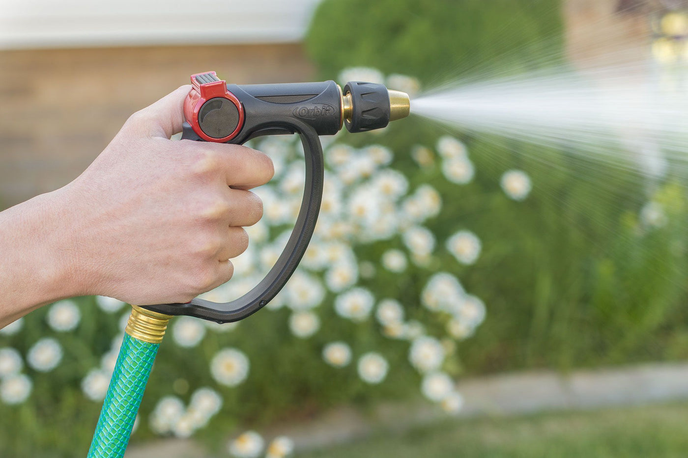 Black and red pro-flo adjustable spray thumb control d-grip brass tip watering nozzle, emitting water.