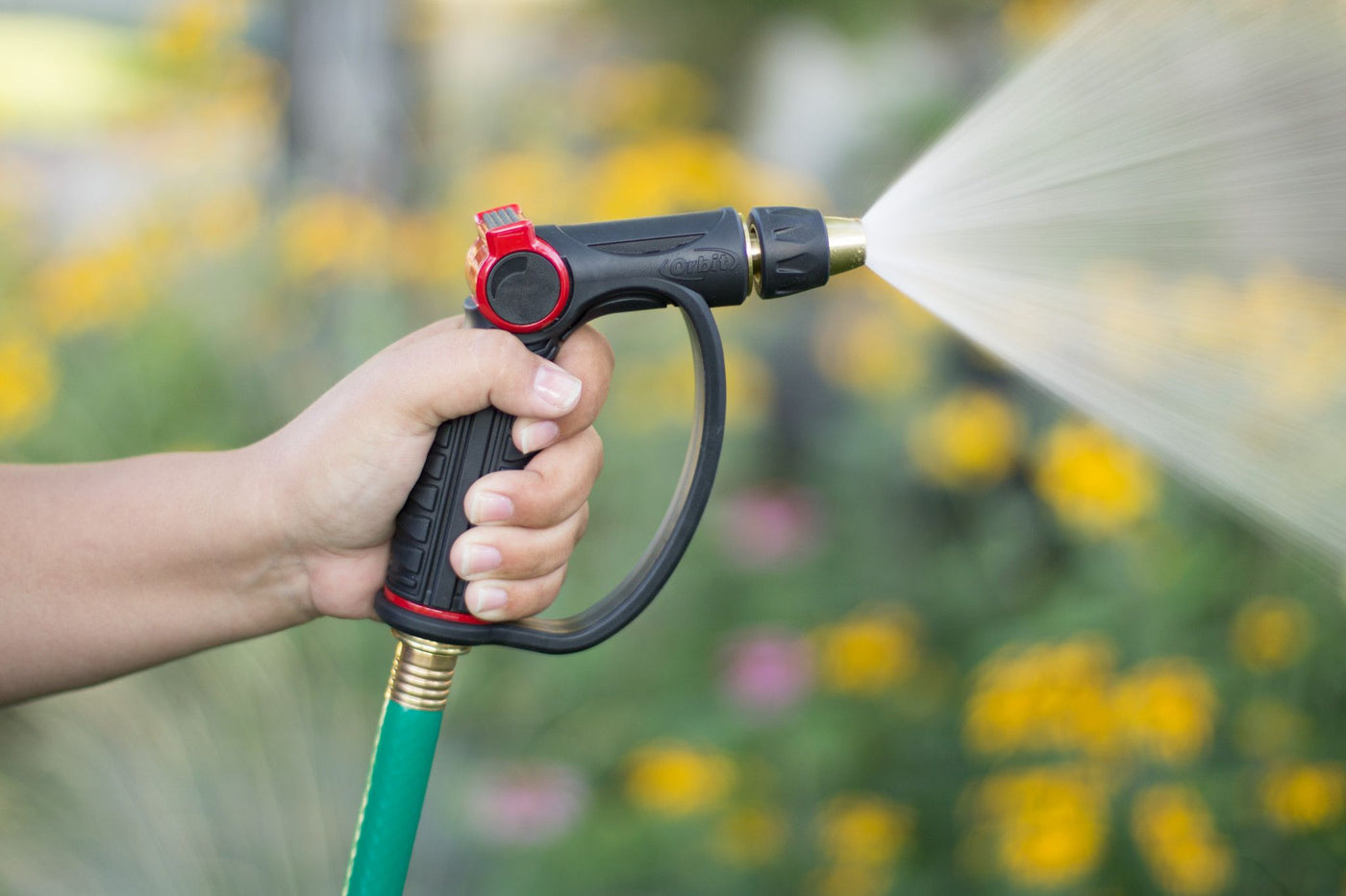 Black and red pro-flo adjustable spray thumb control d-grip brass tip watering nozzle, emitting a wide cone spray of water. 